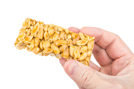 Piece of kozinak from peanuts in male hand isolated on white backgroundの写真素材