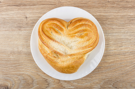 Sweet bun with sugar in white plate on wooden table. Top viewの写真素材