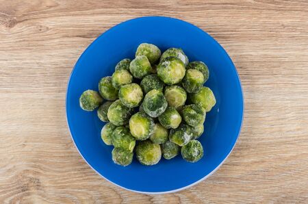 Blue plate with frozen brussels sprouts on wooden table. Top viewの写真素材