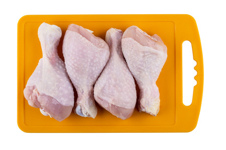 Raw chicken legs on orange cutting board isolated on white background. Top viewの写真素材