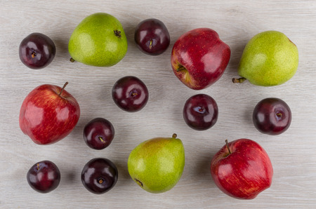 Apples, pears and plums scattered on wooden table. Top view