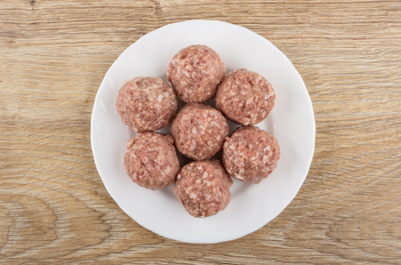 Raw meatballs in white plate on wooden table. Top viewの写真素材