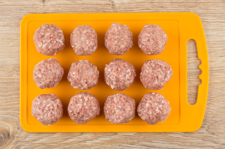 Cutting board with raw meatballs on wooden table. Top viewの写真素材