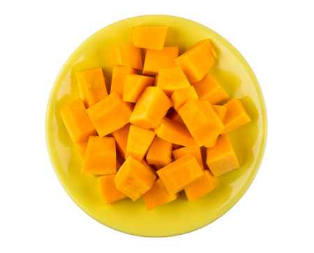 Cubes of pumpkin in yellow plate isolated on white background. Top viewの写真素材