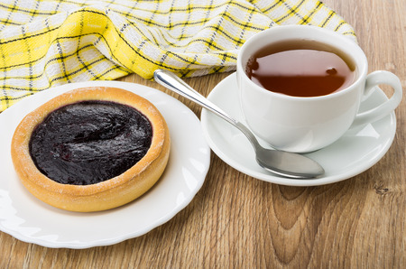 Cup of tea and pie with blueberry jam in plate on wooden tableの写真素材