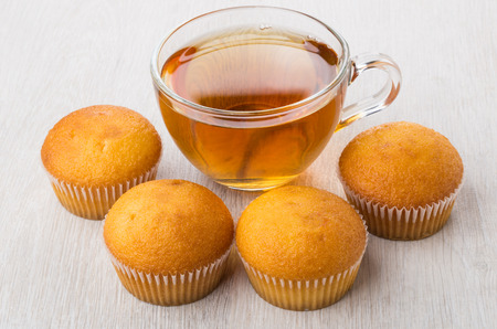 Transparent cup with tea and muffins on wooden tableの写真素材