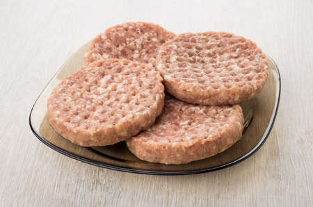 Raw cutlets in brown transparent plate on wooden tableの写真素材