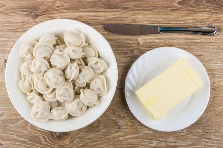 Plate with boiled dumpling, table knife and butter on wooden table. Top viewの写真素材