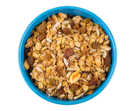 Muesli with oat flakes, peanuts, raisins, sunflower seeds in blue bowl isolated on white background. Top viewの写真素材