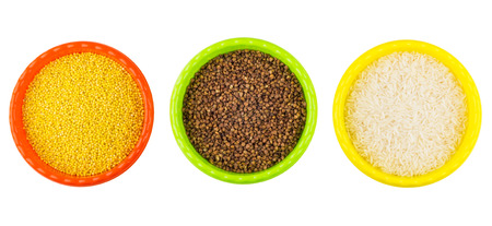 Plastic bowls with millet, buckwheat and rice isolated on white background. Top view