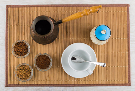 Bowls with instant and ground coffee, turka, sugar bowl, empty cup, spoon on bamboo mat. Top viewの写真素材