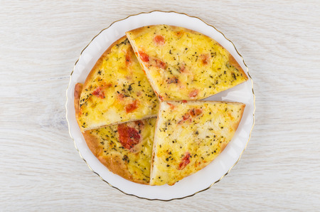 Pieces of flatbread with sour cream and tomato in plate on wooden table. Top view