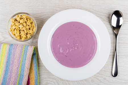 Cornflakes in form star in bowl, blueberry yogurt in plate, spoon, striped napkin on wooden table. Top viewの写真素材