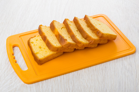 Slices of biscuit on plastic cutting board on wooden tableの写真素材