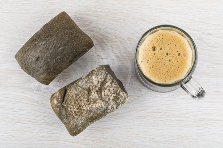 Mug of russian kvass and two bread ciabatta on wooden table. Top viewの写真素材