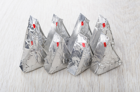 Pieces of melted cheese in aluminium foil on wooden tableの写真素材