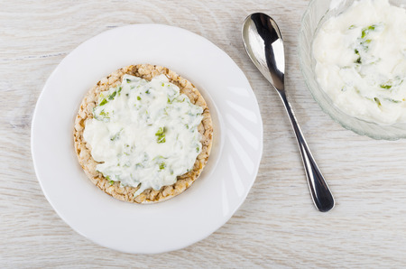 Sandwich with soft cottage cheese and greens, spoon, bowl with cottage cheese on wooden table. Top viewの写真素材