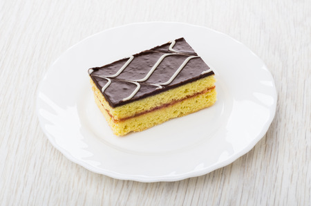 Cake with chocolate on white plate on wooden table