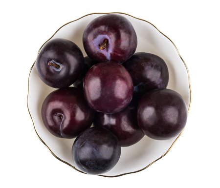 Glass bowl with ripe plums isolated on white background. Top viewの写真素材