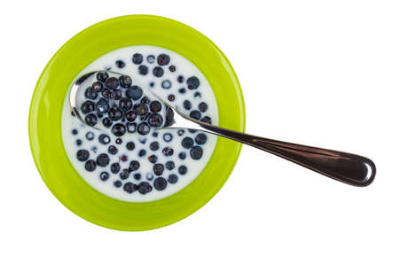 Spoon in green bowl with blueberries and milk isolated on white background. Top viewの写真素材