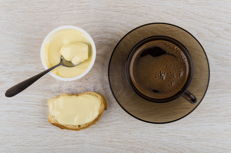 Sweet melted cheese, spoon in jar, sandwich with cheese, coffee in cup on wooden table. Top viewの写真素材