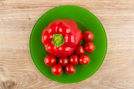 Sweet pepper, tomato cherries in green plate on wooden table. Top viewの写真素材