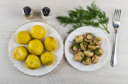 Baked potatoes, mushrooms with dill in plate, salt, pepper, fork on wooden table. Top viewの写真素材
