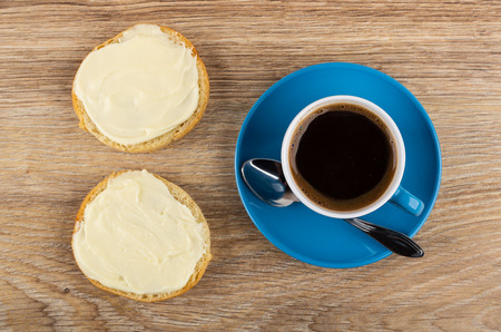 Sandwiches with melted cheese, coffee in cup, spoon on saucer on wooden table. Top viewの写真素材