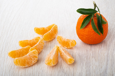 Tangerine with leaves, slices of tangerine on wooden table