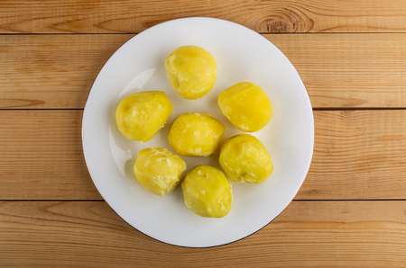 Boiled yellow potatoes in white plate on wooden table. Top viewの写真素材