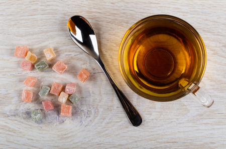 Scattered multicolor rakhat-lukum, cup of tea, teaspoon on wooden table. Top viewの写真素材