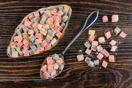 Multicolor rakhat-lukum in plate, scattered cubes of rakhat-lukum and spoon on dark wooden table. Top viewの写真素材