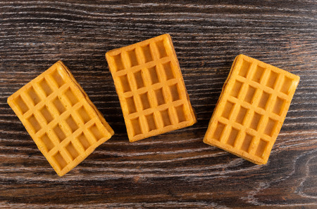 Three soft waffles with filling on dark wooden table. Top view