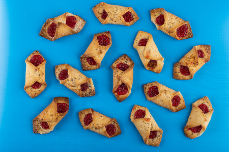 Many shortbread envelope cookies with jam on blue table. Top viewの写真素材