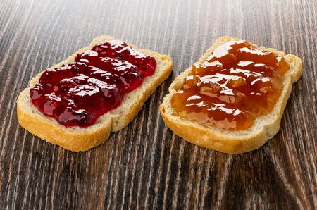Sandwiches with currant jam and apricot jam on dark wooden tableの写真素材