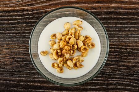 Glass transparent bowl with yogurt and puffed wheat on dark wooden table. Top viewの写真素材