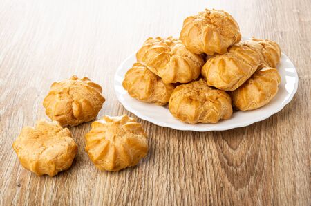 Profiteroles in white glass plate and on wooden tableの写真素材