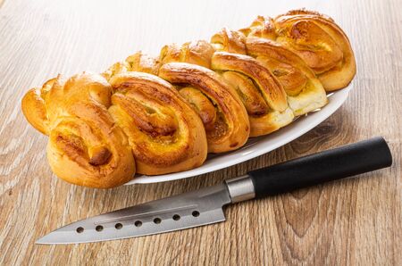 Wicker pie with lemon jam in white dish, kitchen knife on wooden table