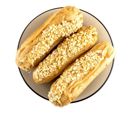 Three eclairs with peanut in brown saucer isolated on white background. Top view
