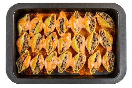 Baked stuffed pasta conchiglie with sauce in dripping pan isolated on white background. Top viewの写真素材