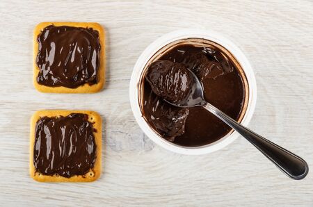 Sandwiches with chocolate melted cheese, spoon in plastic jar with chocolate cheese on wooden table....