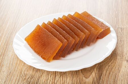 Slices of apple marmalade in white plate on wooden tableの写真素材