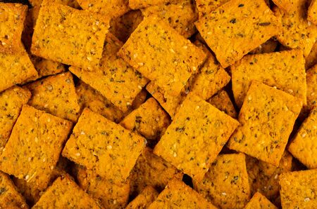 Background from many crackers with tomato, sesame and oregano. Top view