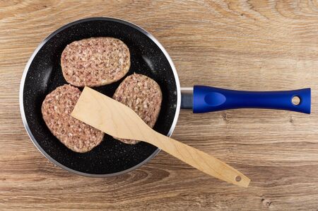 Raw pork cutlets, spatula in frying pan on wooden table. Top viewの写真素材