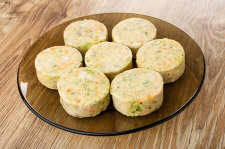 Frozen vegetable cutlets in brown transparent plate on wooden table