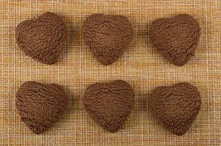 Six chocolate cookies in form heart on brown mat. Top viewの写真素材