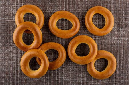 Scattered bread rings on brown mat. Top view