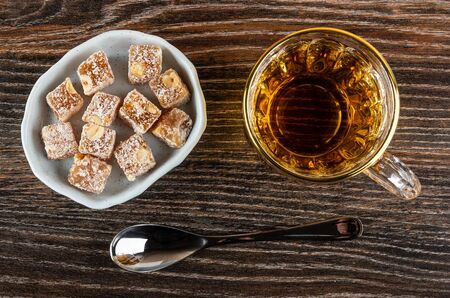 Blue glass bowl with rakhat-lukum, transparent cup with tea, teaspoon on dark wooden table. Top viewの写真素材