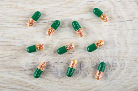 Scattered transparent capsules of medicine on light wooden table. Top view