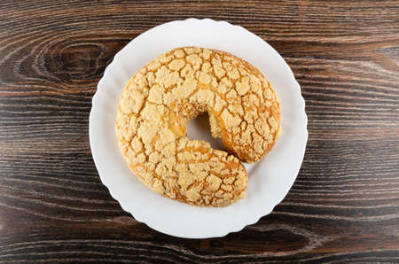 Sprinkled horn-shaped bun in white plate on dark wooden table. Top view